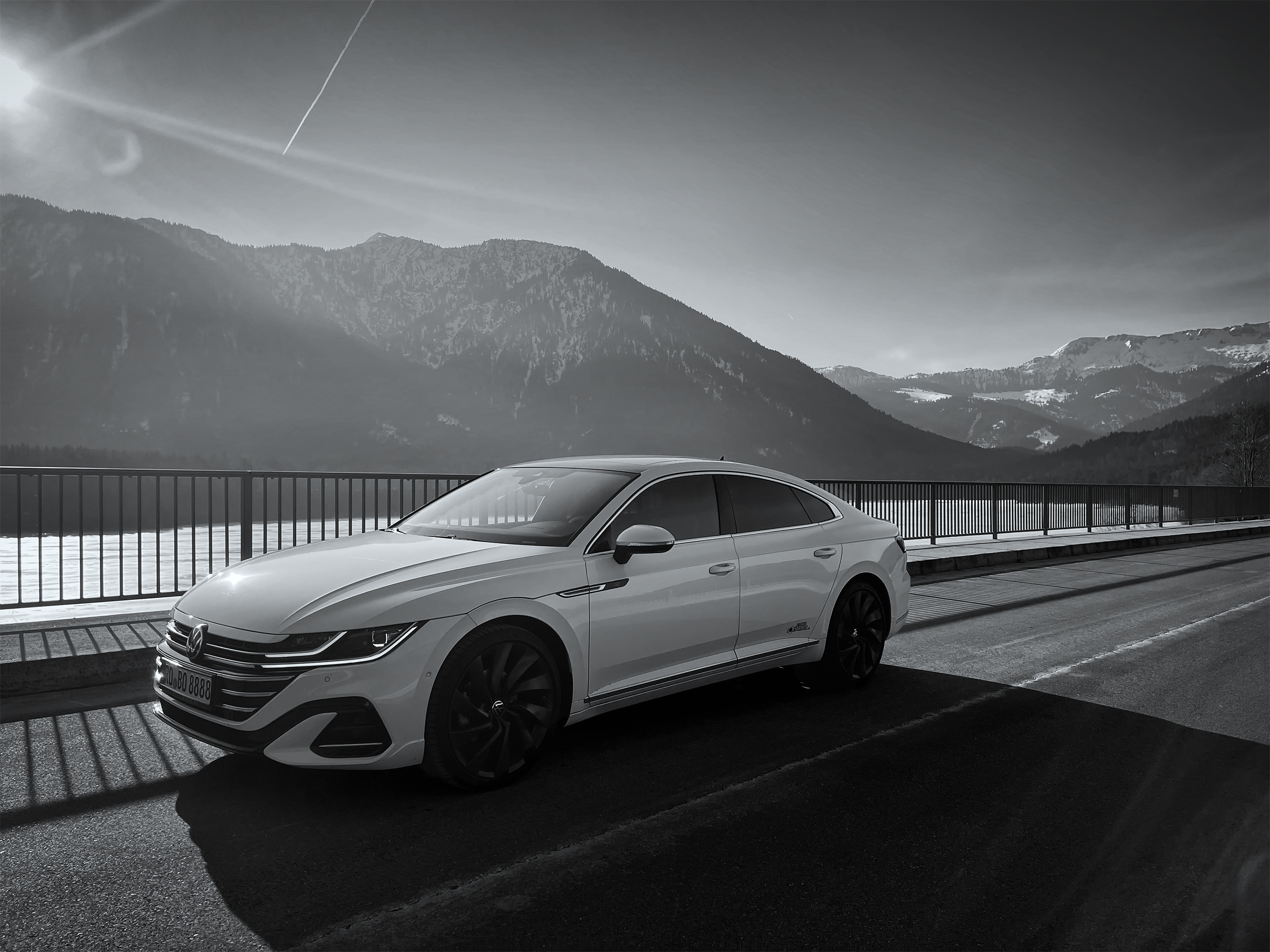 Weißer VW Arteon vor alpinem Bergpanorama in Schwarzweiß-Optik